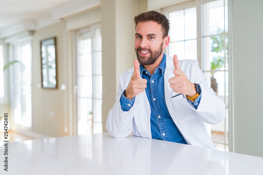 Handsome doctor man wearing medical coat at the clinic pointing fingers to camera with happy and funny face. Good energy and vibes. Handsome doctor man wearing medical coat at the clinic pointing fingers to camera with happy and funny face. Good energy and vibes.