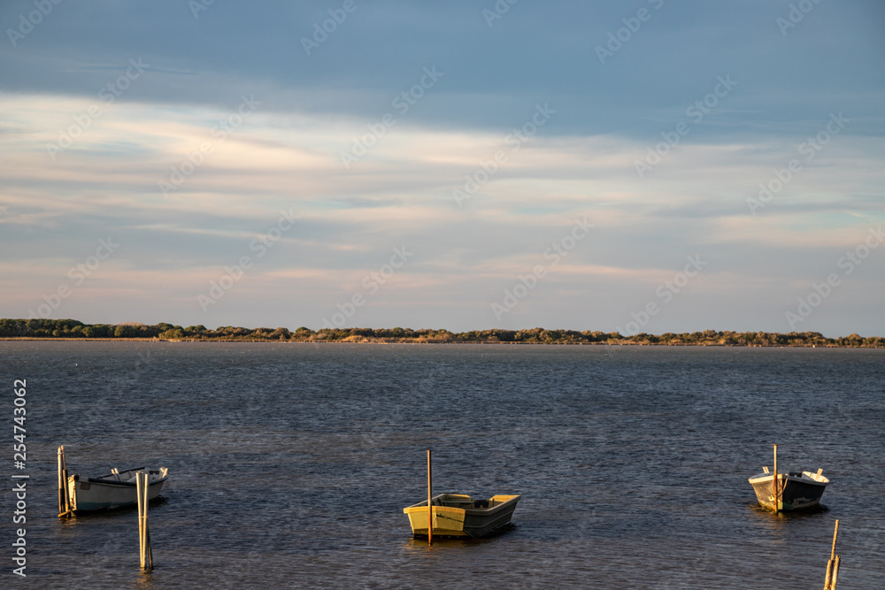 Naklejka premium three boats on the lake of Lesina at sunset. Gargano National Park, Apulia, Italy