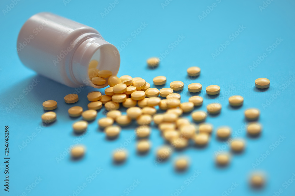 Assorted pharmaceutical medicine pills, tablets and capsules and bottle on blue background. Drugs and various narcotic substances. Copy space for text. Stock photo for design