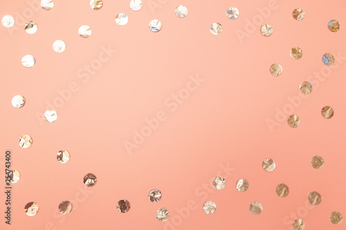 Frame of shiny silver confetti on pastel millennial pink paper background. Concept of holiday, birthday, blogging, beauty. Top view. Flat lay. Minimal style mock up. Lifestyle. Copy space