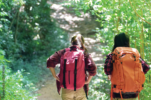 Side view of Two young Asian female hipster hiking in deep forest holiday, wild adventure. Background for Travel concept 