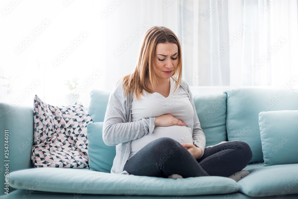 Young pregnant woman suffering from abdominal pain at home Young pregnant woman suffering from abdominal pain at home