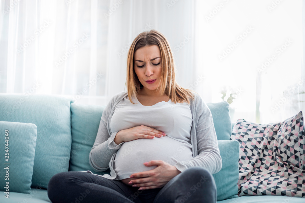 Young pregnant woman suffering from abdominal pain at home