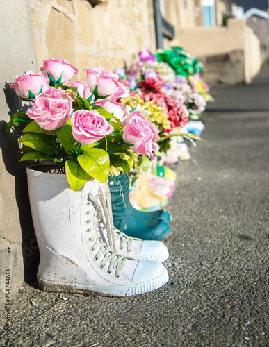 Flowers in old shoes on sidewalk in front of old house