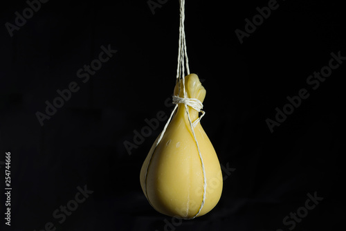 Typical Italian cheese Caciocavallo ripens in ropes in a hanging state on a dark background. photo