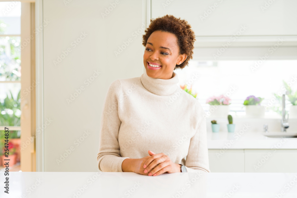 Young beautiful african american woman at home looking away to side with smile on face, natural expression. Laughing confident. Young beautiful african american woman at home looking away to side with smile on face, natural expression. Laughing confident.