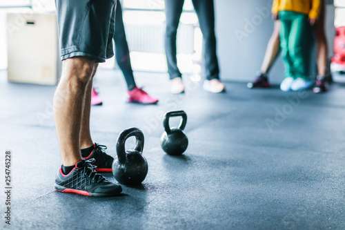 The legs of a group of athletes in the gym before an exercise with weights. Athletes who rest after doing an exercise with a small weight in the gym