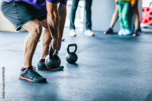 An athlete who is engaged in functional training raises a small weight while performing an exercise while he crouches with a weight, waving it in front of him