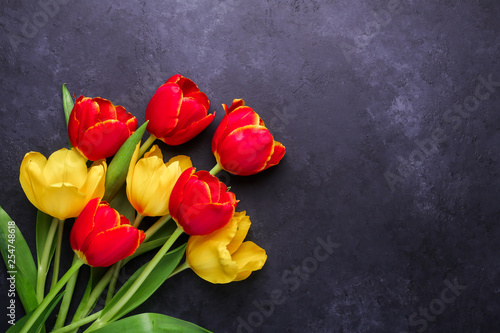 Fresh colorful tulips flowers bouquet on dark stone background