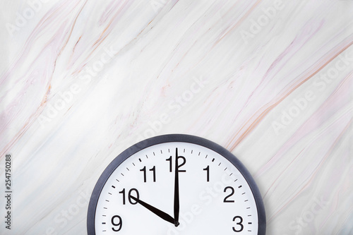 Wall clock show ten o'clock on white marble texture. Office clock show 10pm or 10am on marble background photo