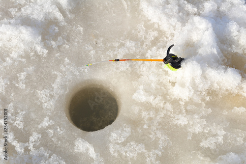 Ice fisherman on frozen winter mountain lake