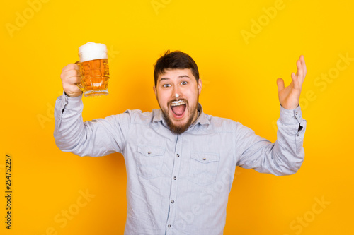 Leinwand Poster funny man with a glass of beer and foam on his mustache and nose on a yellow bac