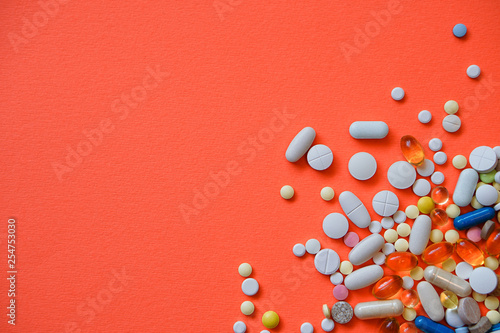 Assorted pharmaceutical medicine pills, tablets and capsules and bottle on red background. Drugs and various narcotic substances. Copy space for text. Stock photo for design