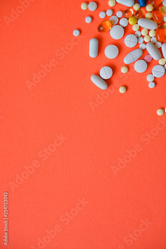 Assorted pharmaceutical medicine pills, tablets and capsules and bottle on red background. Drugs and various narcotic substances. Copy space for text. Stock photo for design