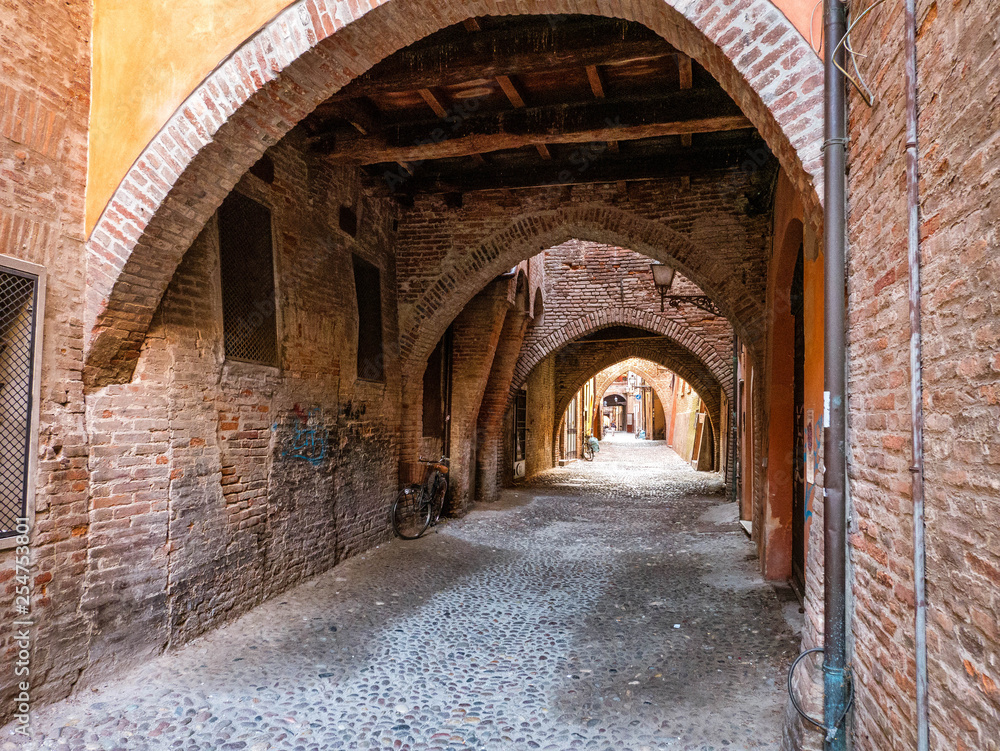 Narrow side street and arches in the medieval town of Ferrara, Italy