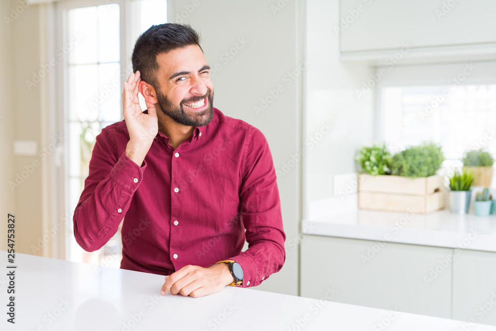 Handsome hispanic business man smiling with hand over ear listening an hearing to rumor or gossip. Deafness concept. Handsome hispanic business man smiling with hand over ear listening an hearing to rumor or gossip. Deafness concept.