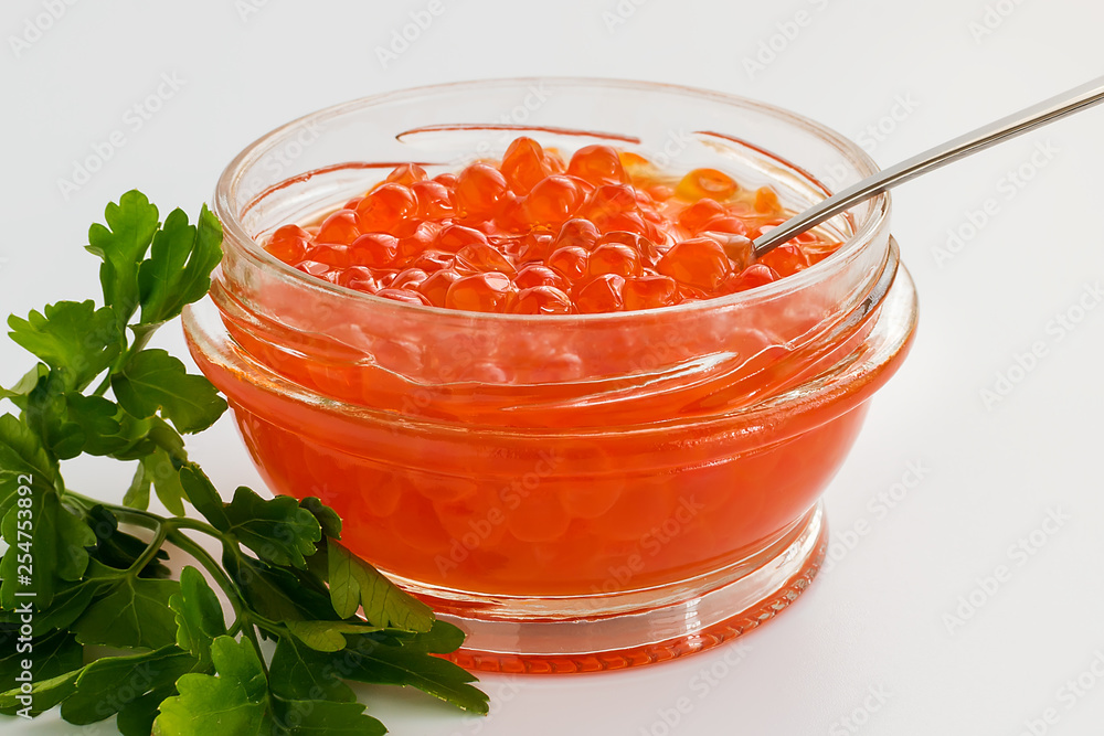 A glass jar of red caviar on a white background. Salmon caviar. Sea fish delicacy. A glass jar of red caviar on a white background. Salmon caviar. Sea fish delicacy.