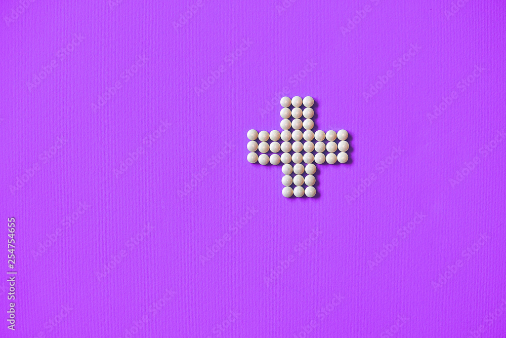Obraz premium Medical cross laid out medicines, white tablets on a blue background. Pharmacology and medicine struggle for health. Drug addiction. Treatment of various diseases
