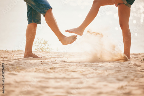 young couple playing with sand. Summer lifestyle. feet in the sand on the beach