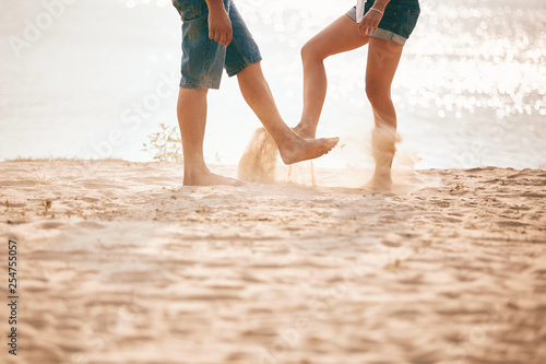 young couple playing with sand. Summer lifestyle. feet in the sand on the beach © Andriy Medvediuk