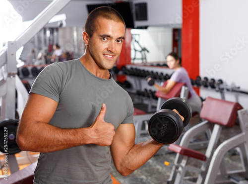 Portrait of muscular guy lifting dumbbells
