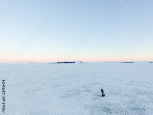 Ice fisherman on frozen winter mountain lake