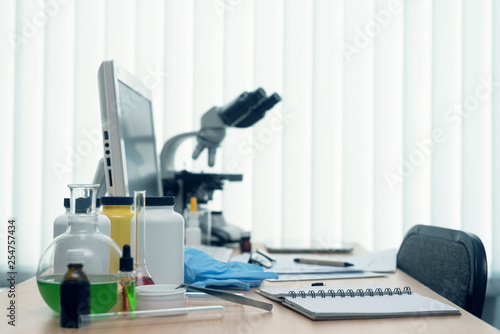 Laboratory table with microscope, flasks and a desktop computer above on a window light background. Medicine, pharmacology, pharmacy abstract background. photo