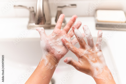 Close up of child washing hands over sink photo