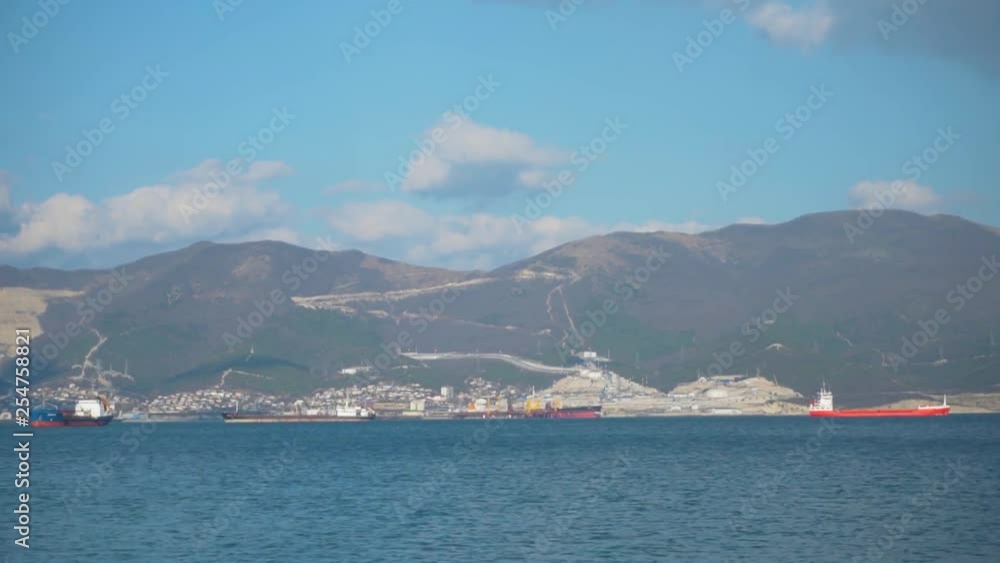 Shooting the movement of cargo ships in the open sea on the background of other ships, mountains, sea and sky. The sea cargo port is visible in the background. Shooting the movement of cargo ships in the open sea on the background of other ships, mountains, sea and sky. The sea cargo port is visible in the background.