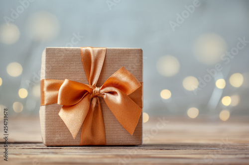 Gift box wrapped with craft paper and bow on neutral background with boke.