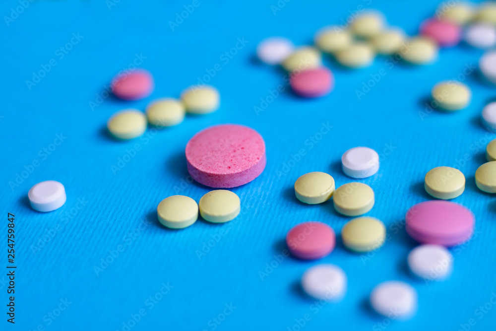 Spilled colored medications and pills on a blue background. Pharmacology and medicine struggle for health. Drug addiction. Treatment of various diseases Spilled colored medications and pills on a blue background. Pharmacology and medicine struggle for health. Drug addiction. Treatment of various diseases