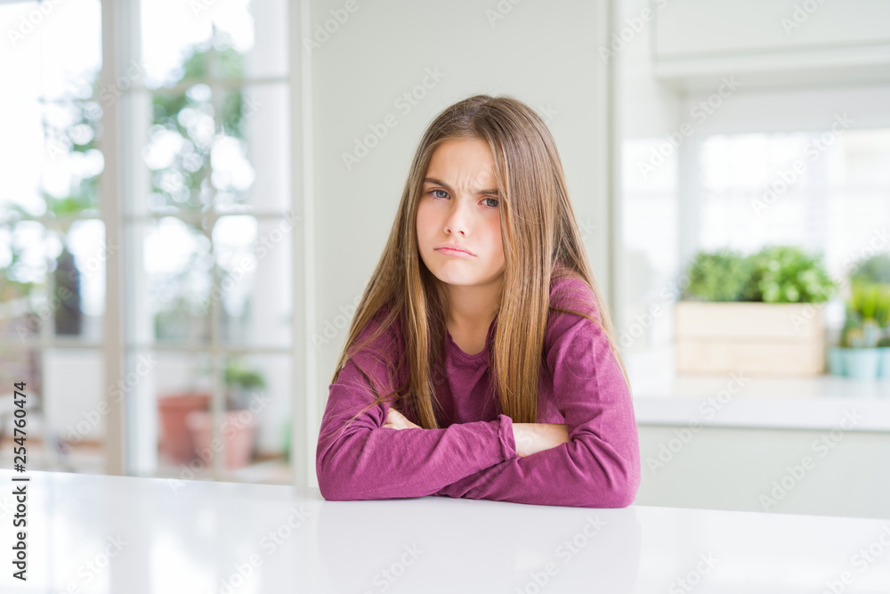 Beautiful young girl kid on white table skeptic and nervous, disapproving expression on face with crossed arms. Negative person. Beautiful young girl kid on white table skeptic and nervous, disapproving expression on face with crossed arms. Negative person.