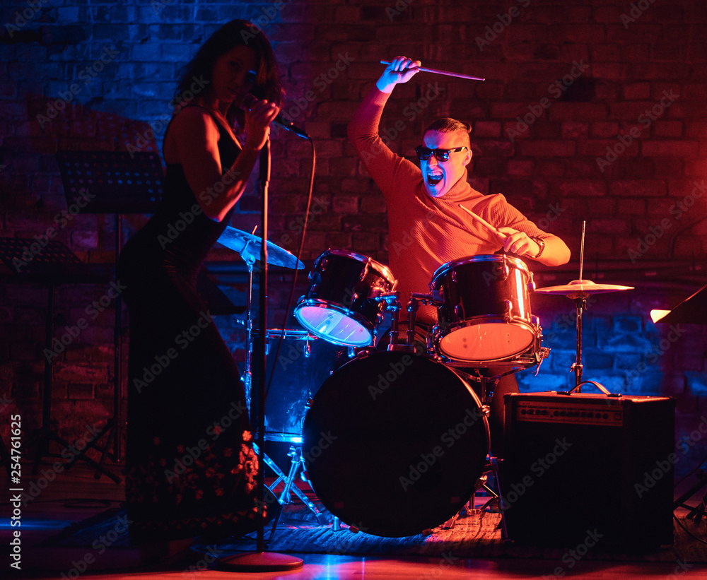 Fototapeta premium Jazz band performance. Young couple of musicians - a drummer and a singer in a nightclub.