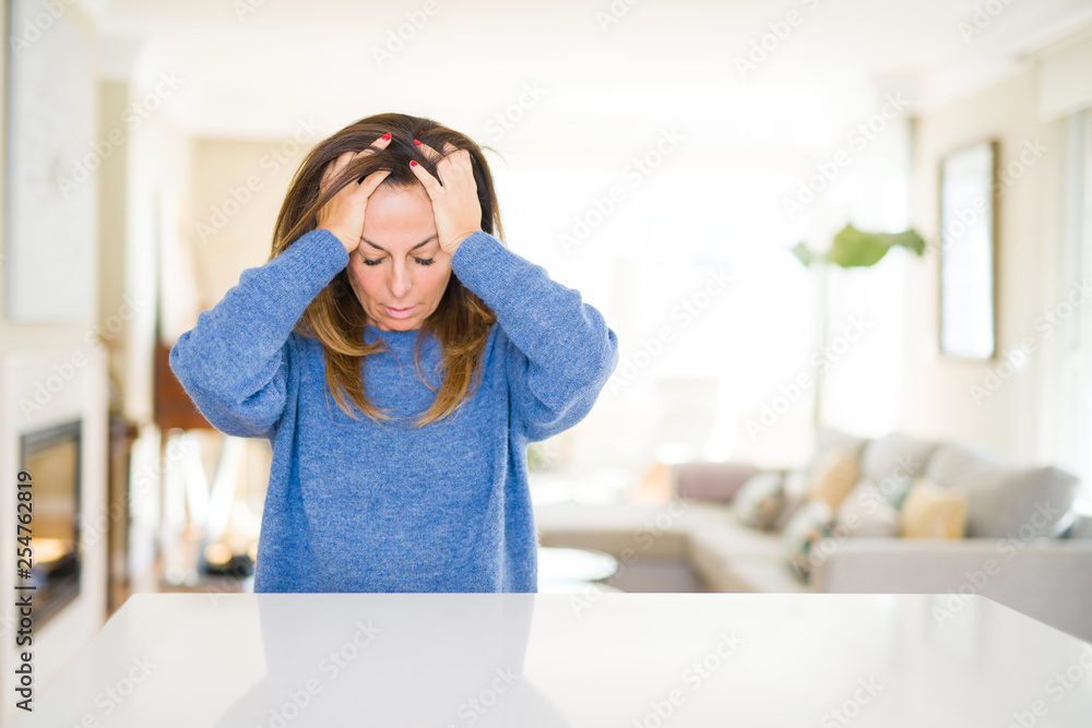 Beautiful middle age woman at home suffering from headache desperate and stressed because pain and migraine. Hands on head. Beautiful middle age woman at home suffering from headache desperate and stressed because pain and migraine. Hands on head.