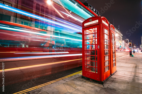Light trails of a double decker bus next to the iconic telephone booth in London