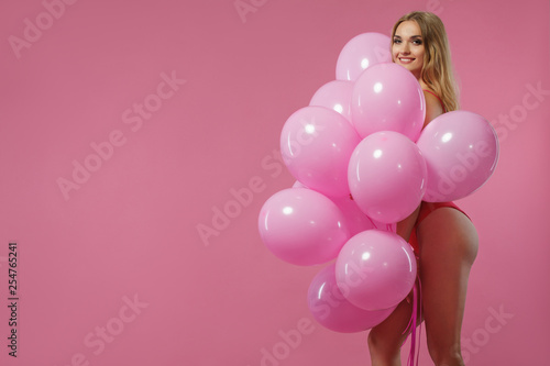 Beauty girl with colorful air balloons laughing over pink background. Beautiful Happy Young woman on birthday holiday party. Joyful model having fun, playing and celebrating with pastel color balloon © Mike Orlov