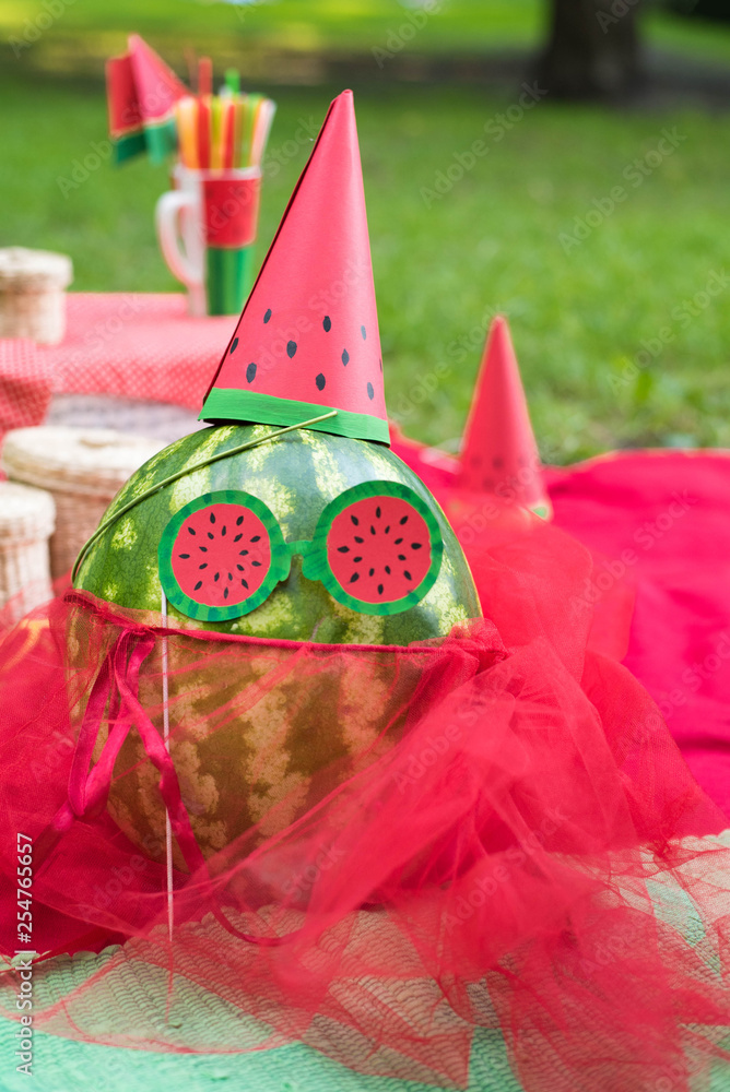 Watermelon party, picnic for children in park. watermelon day. Watermalon wearing cap, dress and glasses.