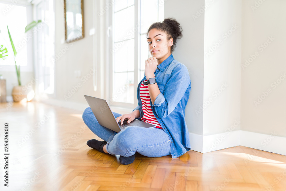 Young african american woman sitting on the floor using computer laptop serious face thinking about question, very confused idea Young african american woman sitting on the floor using computer laptop serious face thinking about question, very confused idea