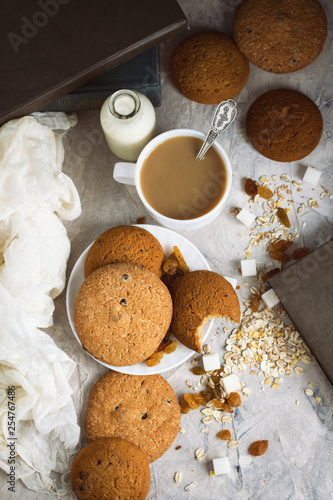 Oatmeal cookies, Books, Oatmeal Flakes, Cup of Coffee with Milk, Raisins on a light background. The concept of Good Morning and Breakfast. Top view