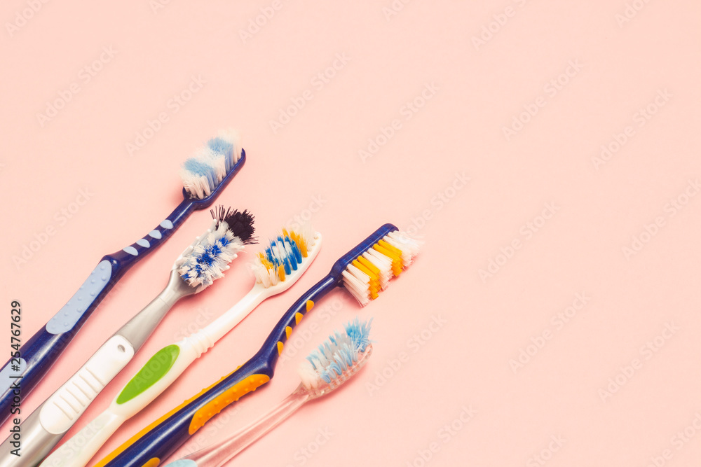 Several different used toothbrushes on a pink background. Toothbrush change concept, oral hygiene, big and friendly family, toothbrush selection. Flat lay, top view. Several different used toothbrushes on a pink background. Toothbrush change concept, oral hygiene, big and friendly family, toothbrush selection. Flat lay, top view.