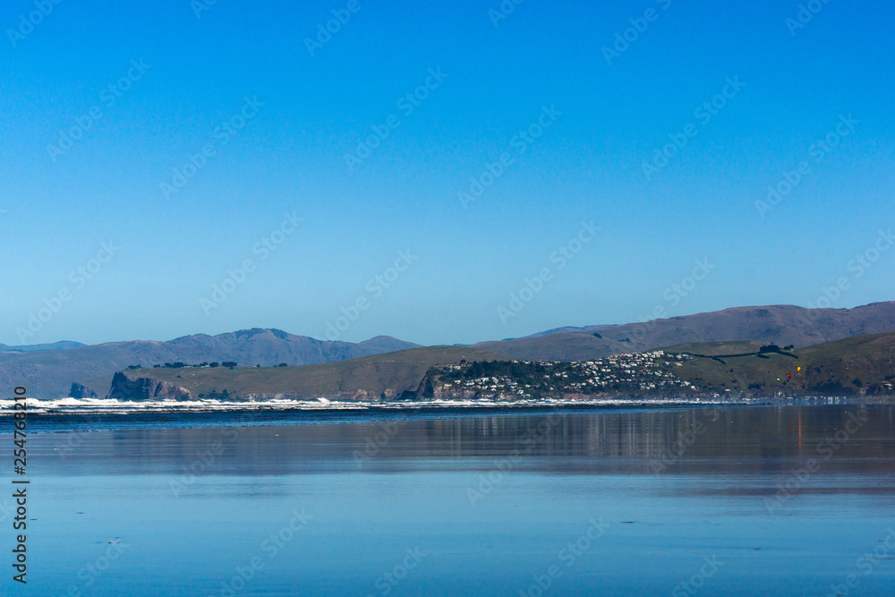 empty vast beach covered with water, seascape with coast line and mountains on the horizon