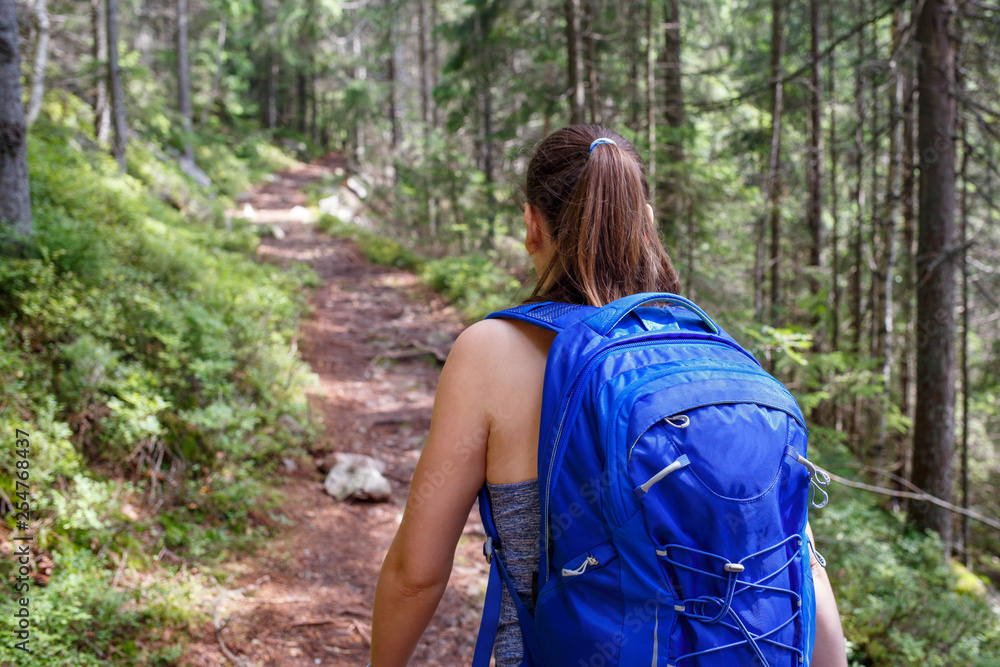 Young smiling woman with backpack hiking in forest Young smiling woman with backpack hiking in forest