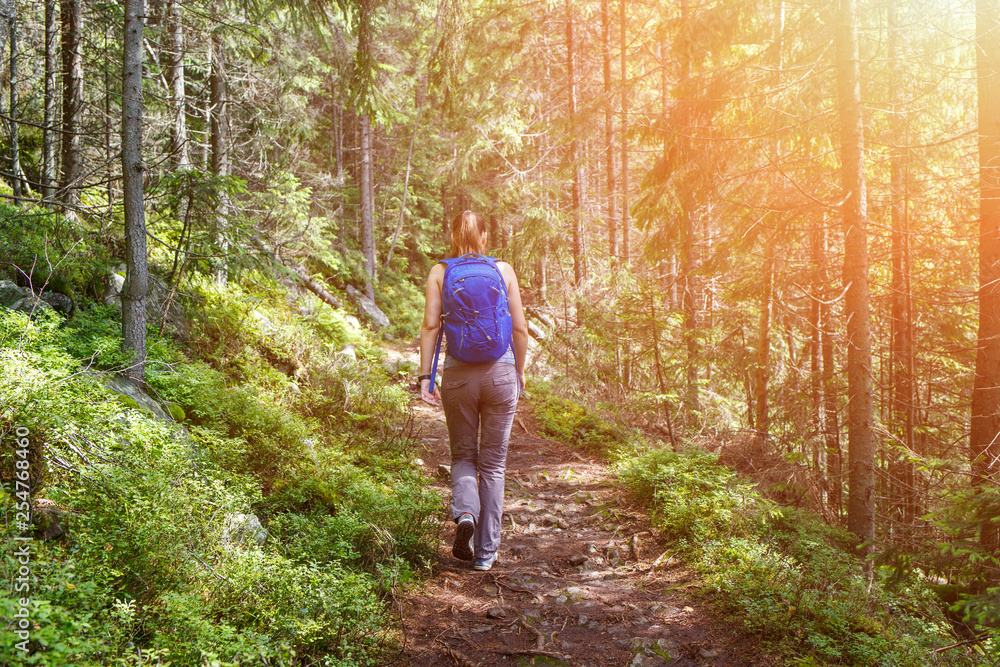 Young happy backpacker woman walking in woods Young happy backpacker woman walking in woods