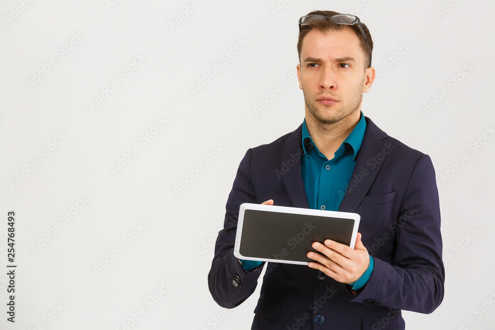 Using modern technologies. Handsome young man in shirt looking at his digital tablet and smiling while standing against background Using modern technologies. Handsome young man in shirt looking at his digital tablet and smiling while standing against background