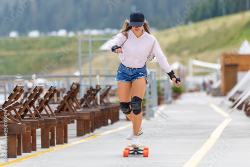 Young girl with pads longboarding near beach