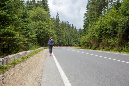 Young smiling woman jogging on mountain road.
