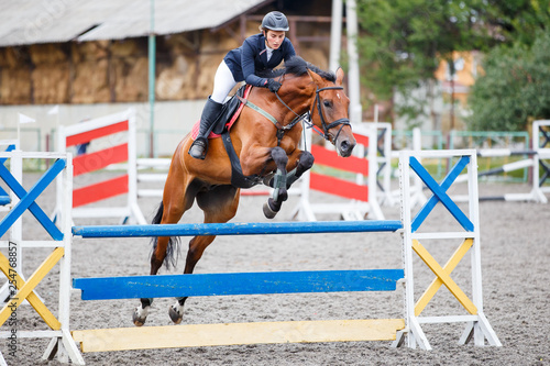 Young woman riding horse on show jumping contest