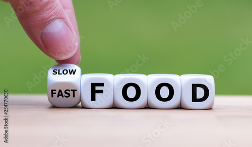 Hand turns a dice and changes the expression "fast food" to "slow food".