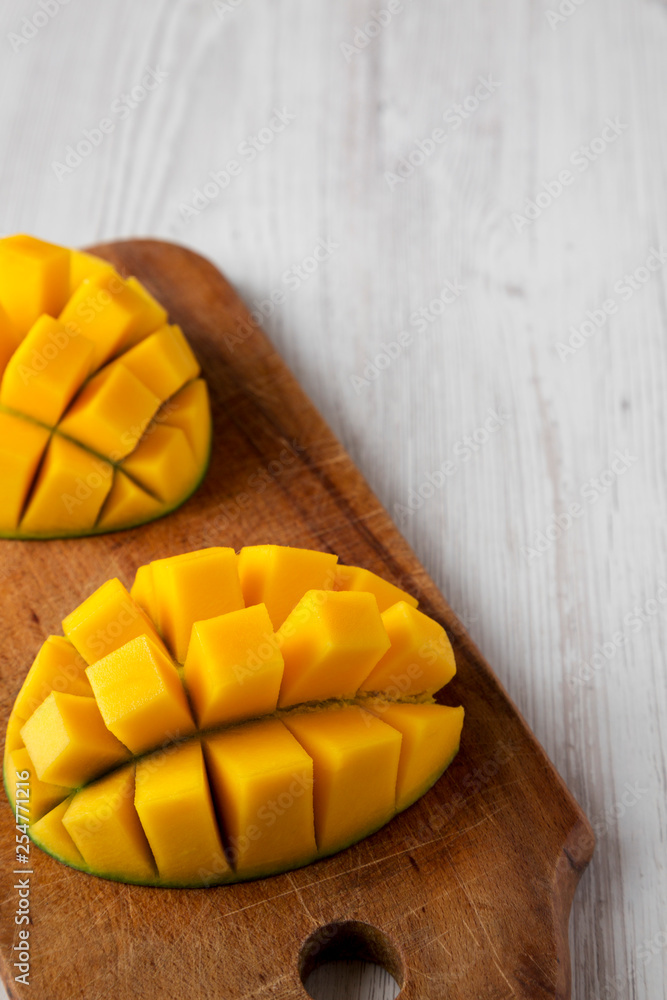 Sweet mango on rustic wooden board on a white wooden table, low angle view. Close-up. Copy space. Sweet mango on rustic wooden board on a white wooden table, low angle view. Close-up. Copy space.