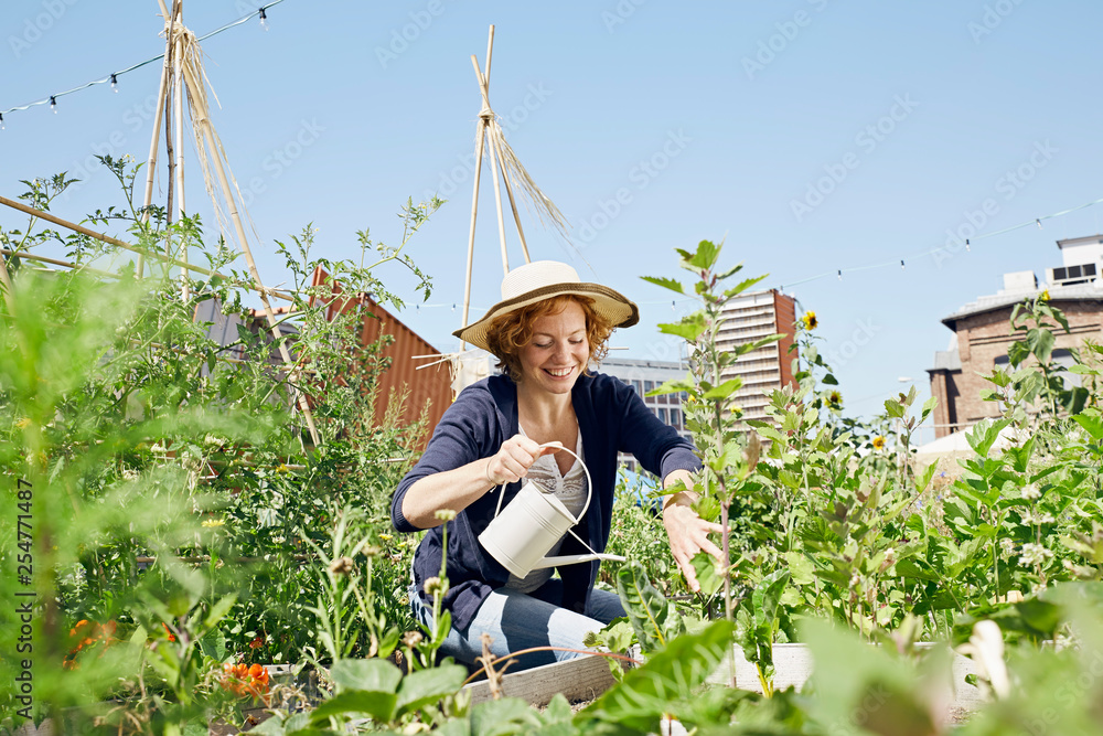 Smiling young woman wearing straw hat urban gardening